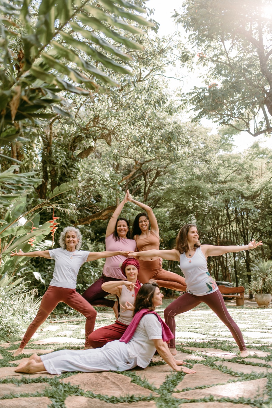 Turma da formação de instrutores de yoga reunida em pose de grupo ao ar livre no Sítio Geranium