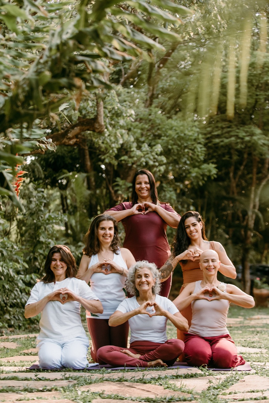 Grupo de yoga reunido fazendo coração com as mãos